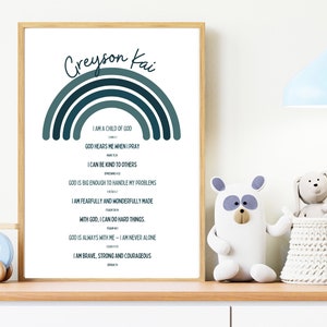 May include: A framed print featuring a rainbow design and the name "Creyson Kai" at the top. The rainbow is made up of shades of blue and green. The print includes a list of positive affirmations, such as "I am a child of God" and "God hears me when I pray".