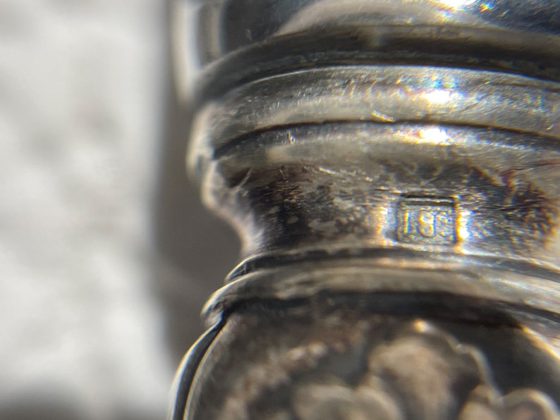 May include: Close-up of a silver object with a hallmark that reads "15E".