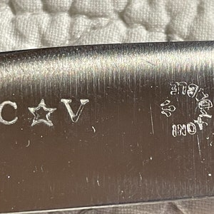 May include: Close-up of a silver blade with the inscription "C * V" and "INOX" in a circle.