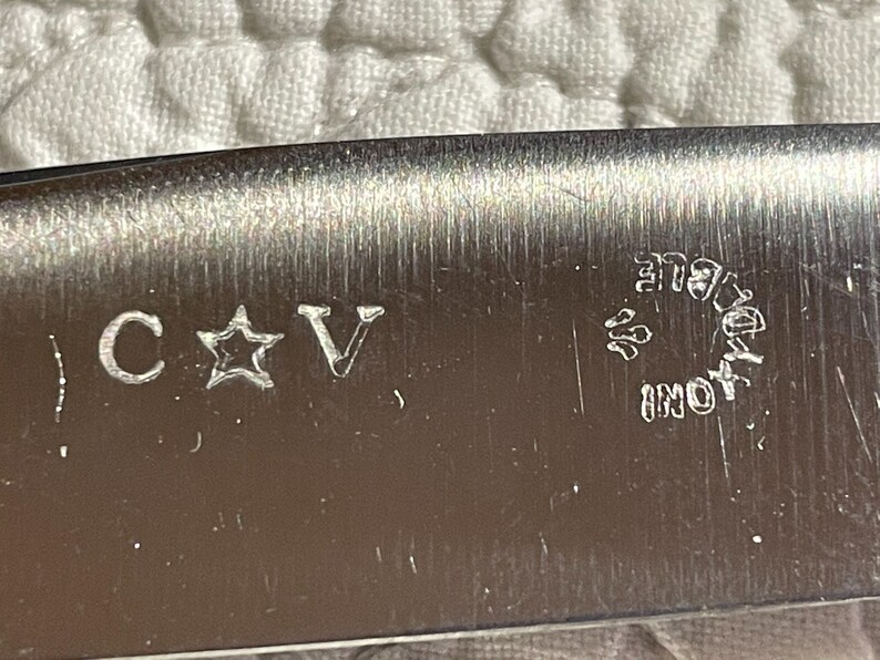 May include: Close-up of a silver blade with the inscription "C * V" and "INOX" in a circle.