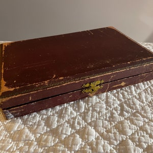 May include: A vintage wooden box with a brass latch. The box is dark brown and has a worn, distressed finish.