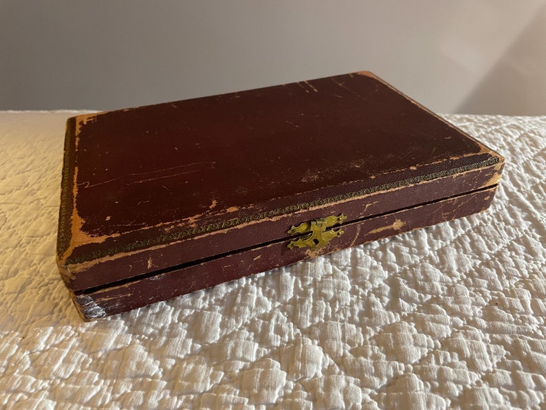 May include: A vintage wooden box with a brass latch. The box is dark brown and has a worn, distressed finish.