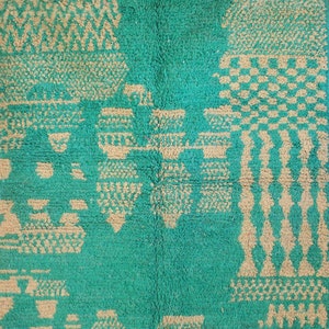 May include: A rectangular rug featuring a vibrant green background with a contrasting beige geometric pattern. The design consists of various abstract shapes, including checkered blocks, vertical columns, and repeating zigzag lines.
