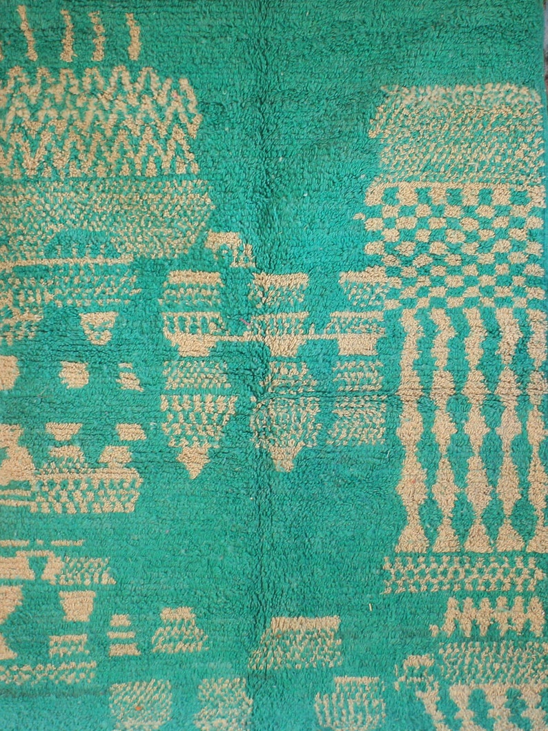 May include: A rectangular rug featuring a vibrant green background with a contrasting beige geometric pattern. The design consists of various abstract shapes, including checkered blocks, vertical columns, and repeating zigzag lines.
