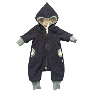 May include: A dark gray hooded baby jumpsuit with a full-length zipper. The hood and cuffs are light gray. The interior of the hood and pocket details feature a patterned fabric with animal illustrations. The jumpsuit has two front pockets.