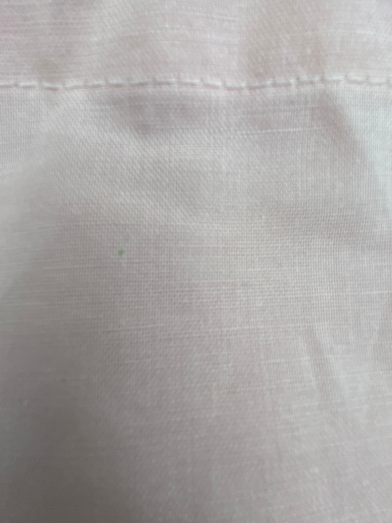 May include: Close-up of a white fabric with a subtle texture. The fabric has a smooth, even surface with a slight sheen.