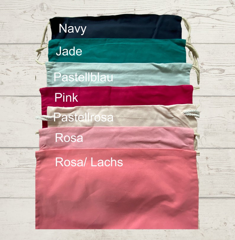 May include: A set of seven drawstring bags in various colors, including navy, jade, light blue, pink, cream, light pink, and coral. The bags are lined up vertically, with the color names written in white text on each bag.