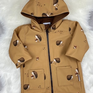 May include: A brown hooded jacket with a zipper closure and two pockets. The jacket has a hedgehog print with brown mushrooms.
