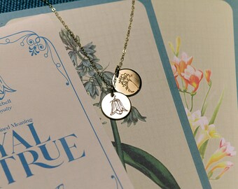 May include: A gold necklace with two charms, each featuring a delicate engraved bluebell flower. The necklace is displayed on a card with the text "Bluebell Loyalty" and "Combined Meaning LOYAL & TRUE".