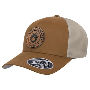 May include: A brown baseball cap with a beige mesh back and a circular leather patch on the front featuring a gorilla graphic and the text THE LEATHER PATCH.COM HAT CO. A black sticker on the brim displays the text FLEXFIT TECH 110 ONE TEN.