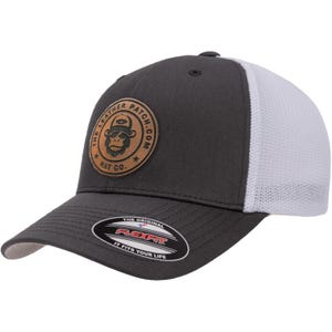 May include: A charcoal gray baseball cap with a white mesh back and a circular tan leather patch on the front. The patch features a gorilla graphic and the text THE LEATHER PATCH.COM HAT CO. A black sticker on the brim reads THE ORIGINAL FLEXFIT.