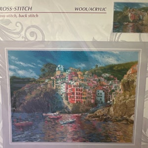 May include: A cross-stitch pattern featuring a colourful cityscape with buildings on a cliff overlooking a blue body of water. The pattern is titled "Liguria" and is 15 3/4 inches by 11 3/4 inches.