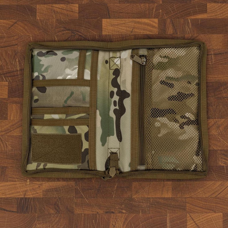 Pu&ograve; includere: Organizer piatto aperto con motivo mimetico e pi&ugrave; scomparti. Include tasche trasparenti, una tasca con cerniera e una tasca a rete. L'organizer &egrave; realizzato in tessuto resistente e ha una chiusura con cerniera. La combinazione di colori include sfumature di verde, marrone e beige.