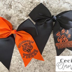 May include: Two black and orange cheer bows with the text "Edwardsville Tigers" and a tiger paw print.