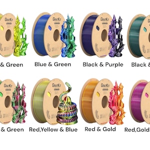 May include: Six spools of filament for 3D printing, each with a different color combination. The filament is wound around a cardboard spool with the text "GRATKIT" printed on it. The colors are yellow and green, blue and green, black and purple, black and green, red and green, red, yellow and blue, red and gold, and red, gold and purple.