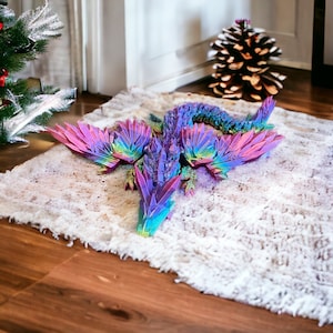 May include: A colorful iridescent dragon figurine with wings spread out, made of a crystal-like material. The dragon is lying on a white fluffy rug.