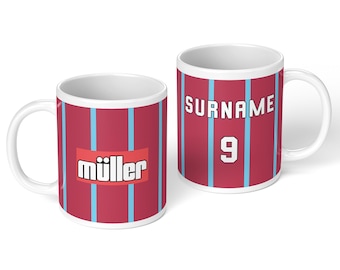 Puede incluir: Dos tazas de cerámica blanca con un patrón de rayas verticales en granate y azul claro. Una taza muestra el texto "müller" en un recuadro blanco, mientras que la otra muestra el texto "SURNAME" sobre el número "9" en fuente blanca.
