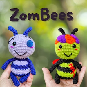 May include: Two handmade crochet bee dolls. One is lavender and blue with a button eye and stitched details. The other is green and black with a red stitched detail. The text "ZomBees" is above the dolls.