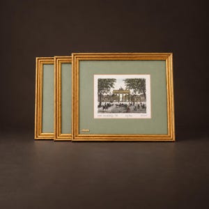 Peut inclure: Trois cadres rectangulaires dorés avec un passe-partout vert sauge, contenant chacun une impression de la porte de Brandebourg à Berlin. L'impression centrale porte le texte "Das Brandenburger Tor", "Berlin" et "Germany" en encre noire.