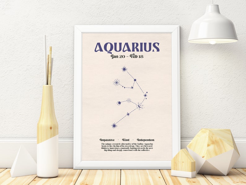 May include: A white framed poster with a light pink background featuring the zodiac sign Aquarius. The constellation is depicted in blue with a crescent moon and stars. The text "Aquarius Jan 20 - Feb 18" is at the top of the poster. Below the constellation, the text "Inquisitive - Kind - Independent" is displayed. The poster describes the personality traits of Aquarius.