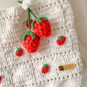 Strawberry Crochet HandBag.
This bag is unique because it has a strawberry pattern attached to the top of this white bag. This bag is also equipped with a strawberry hanger which will certainly beautify this bag.