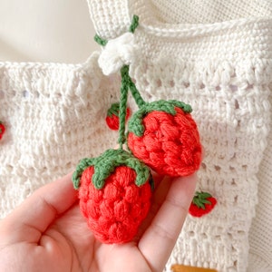 Strawberry Crochet HandBag.
This bag is unique because it has a strawberry pattern attached to the top of this white bag. This bag is also equipped with a strawberry hanger which will certainly beautify this bag.