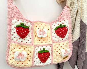 May include: A pink crocheted tote bag with a strawberry and butterfly design. The bag is made of yarn and has a square shape.