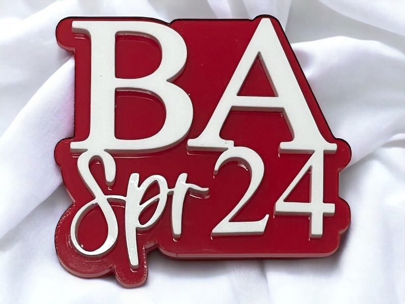 May include: Red and white plastic sign with the letters "BA" in white and the text "Spr 24" in white.