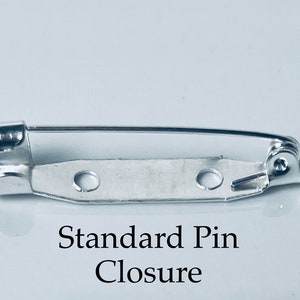 May include: A silver standard pin closure for attaching jewelry or other items to clothing. The pin has a spring-loaded mechanism and a safety catch.