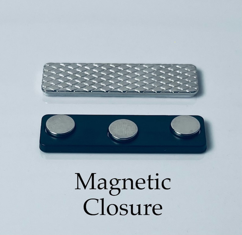 May include: A silver magnetic closure with a textured surface. The closure has three black magnets. The text "Magnetic Closure" is printed below the closure.