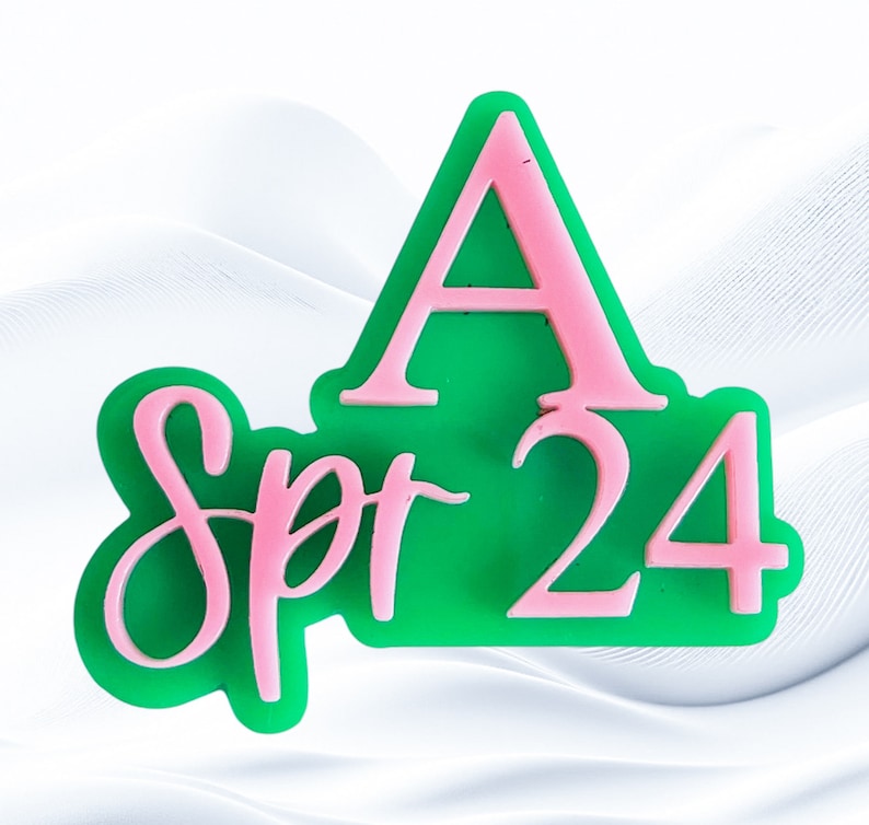 May include: A green and pink acrylic sign with the text "Spr 24" and a large pink letter "A" above the text.