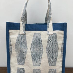 May include: A blue and white tote bag with a geometric pattern. The bag has a blue canvas lining and two blue canvas handles.