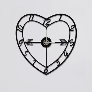 May include: Black heart-shaped wall clock with Roman numeral markings and arrow-shaped hands.