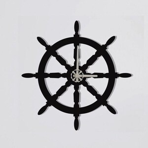 Puede incluir: Un reloj de rueda de barco negro en una pared blanca sobre un armario de madera clara.