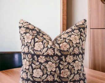May include: A decorative pillow with a floral pattern. The pillow is black with a cream and brown floral design.