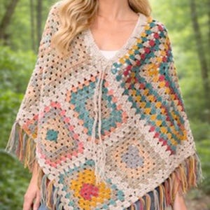 May include: A crochet poncho featuring a multi-colored granny square pattern in shades of beige, teal, yellow, pink, and grey. The garment has a V-neckline with a drawstring tie and is finished with long, multi-colored fringe along the bottom hem.