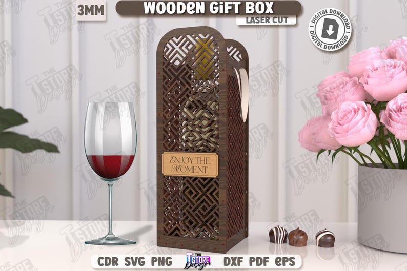 May include: A laser-cut wooden gift box with a geometric design, holding a wine bottle. The box has a label that reads "ENJOY THE MOMENT." A wine glass with red wine and a bouquet of pink roses are also present. The text "WOODEN GIFT BOX" is visible.