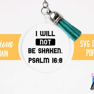 Pu&ograve; includere: Un portachiavi rotondo e trasparente con un design in bianco e nero che recita "I WILL NOT BE SHAKEN. PSALM 16:8". Il portachiavi ha un pon pon turchese.