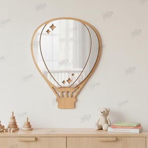 May include: A wooden hot air balloon mirror with a mirrored center and star cutouts. The mirror is mounted on a white wall above a wooden dresser. The dresser has a teddy bear, books, and wooden toys on top.