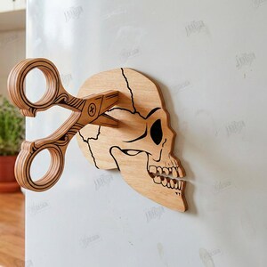 Puede incluir: Decoraci&oacute;n de pared de calavera de madera con tijeras que la atraviesan. La calavera es de color marr&oacute;n claro con detalles negros, y las tijeras tienen un dise&ntilde;o intrincado. La imagen incluye el texto "CUT READY FILE DIGITAL DOWNLOAD".