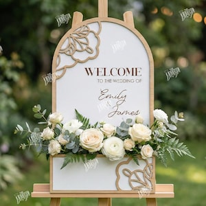 May include: A wooden wedding welcome sign with the text "WELCOME TO THE WEDDING OF Emily & James". The sign is decorated with floral arrangements and a decorative wooden frame. The sign is on an easel.