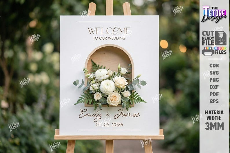 May include: A white wedding welcome sign on an easel, featuring a floral arrangement in a wooden arch. The sign reads "Welcome to our Wedding" and includes the names "Emily & James" and the date "01.05.2026".