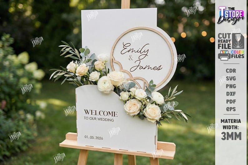 May include: A white wedding sign on a wooden easel, featuring the names "Emily & James" and the date "01.05.2026". The sign is decorated with flowers and greenery, with a wooden frame and a scalloped edge.