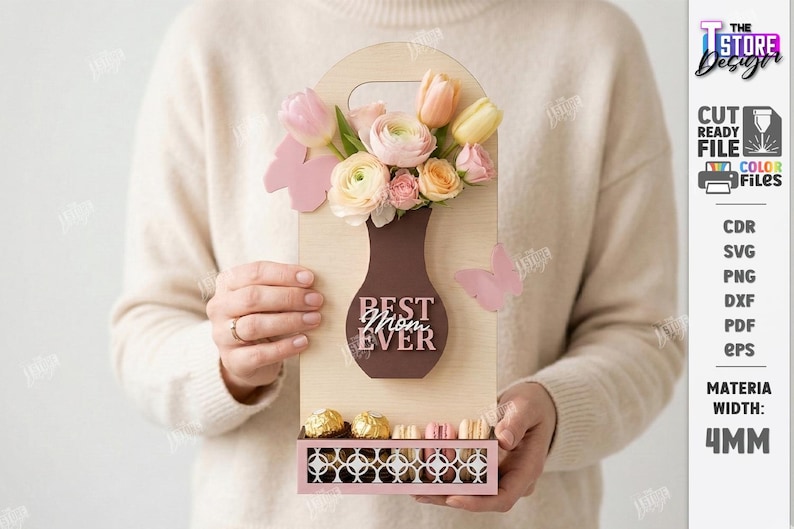 May include: A wooden gift box with a vase-shaped cutout holding flowers and the text "BEST MOM EVER." The box also features a lower compartment with chocolates. Pink butterflies and flowers add a decorative touch.
