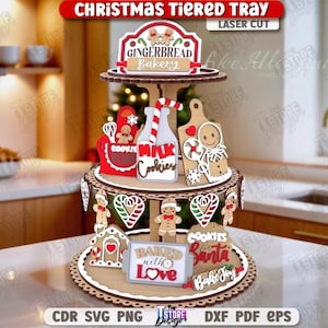 Puede incluir: Una bandeja navideña de tres niveles con decoraciones de madera cortadas con láser. El nivel superior presenta un letrero de "Gingerbread Bakery". El nivel intermedio tiene una botella de leche, un hombre de jengibre y un delantal. El nivel inferior tiene una casa de jengibre y un letrero que dice "Baked with Love".