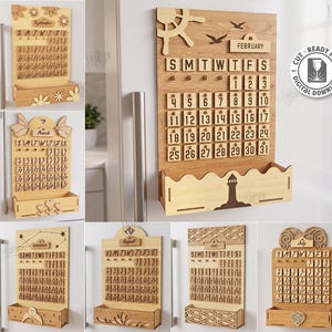 May include: A collection of ten laser-cut wooden wall calendars featuring various decorative themes, including a lighthouse, flowers, and celestial patterns. Each calendar includes a monthly grid, days of the week, and a storage pocket at the base.