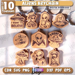 May include: A collection of ten laser-cut wooden alien keychains. Each keychain features a unique alien design, including aliens in a UFO, with a cat, and surfing. The keychains have a light brown color and include the text "I WANT TO BELIEVE" and "I WANT TO LEAVE".