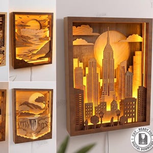 Op de afbeelding: Een collectie van vijf gelaagde houten wandlampen met ingewikkelde lasergesneden ontwerpen van een stadsskyline, berglandschap, waterval, safariscène en zonsondergang. Elk rechthoekig frame wordt van binnenuit verlicht.