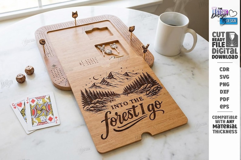 K&ouml;nnte beinhalten: Holz-Cribbage-Brett mit eingravierter Berg- und Waldszene, W&uuml;rfeln, Spielkarten und dekorativen Stiften. Der Text "Into the forest I go" ist auf dem Brett zu sehen. Eine wei&szlig;e Tasse ist ebenfalls vorhanden.