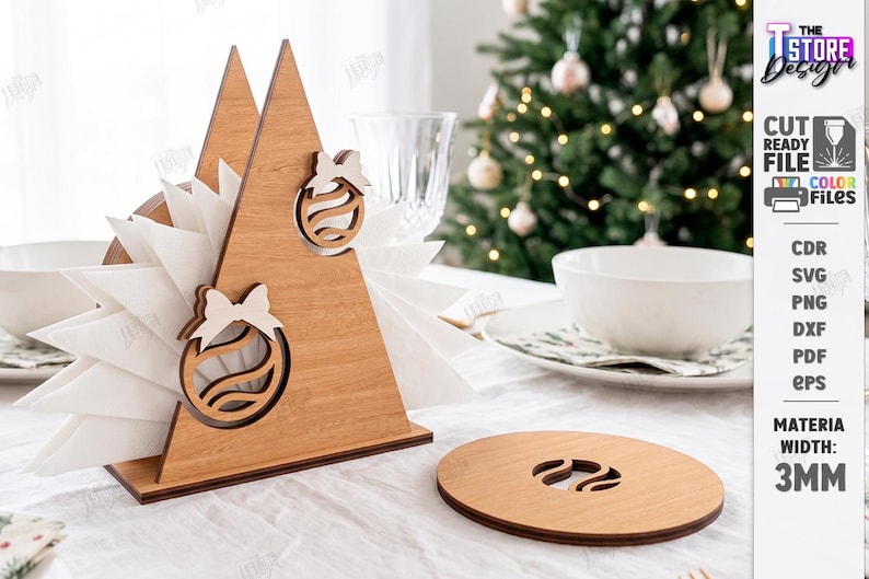 May include: A triangular wooden napkin holder featuring two cutout Christmas ornament designs with bows, holding white napkins. Beside it sits a circular wooden coaster with a matching ornament cutout. Text on the right indicates 3MM material width.